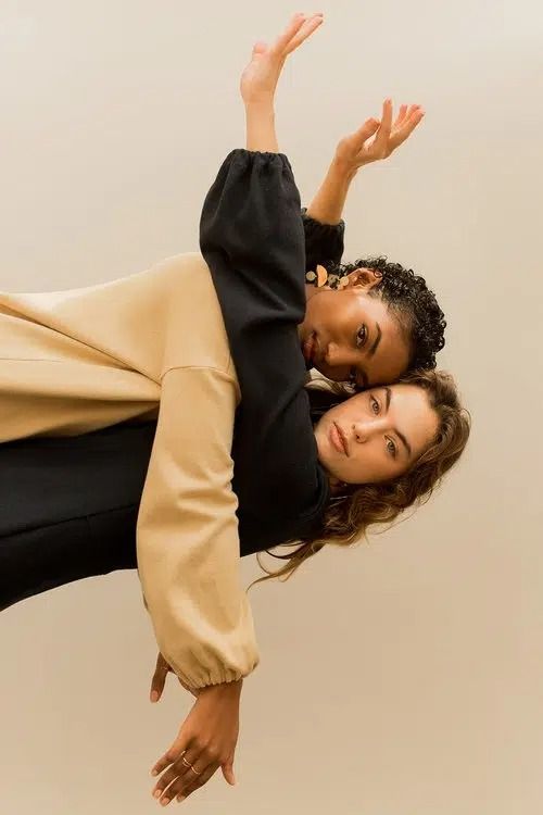 two women are posing for the camera with their hands in the air and one is upside down