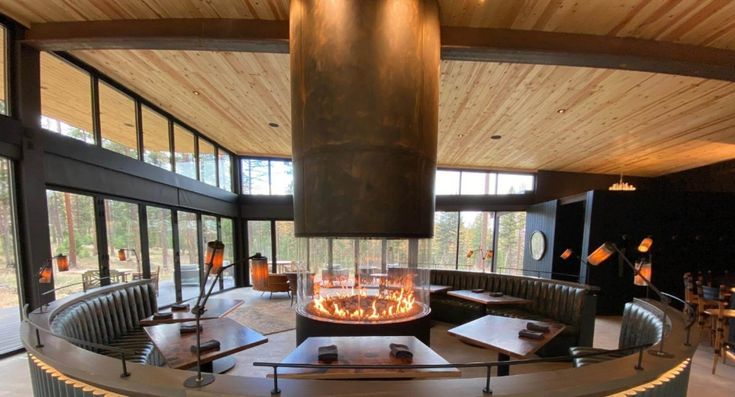 a fire place in the middle of a room with lots of tables and chairs around it