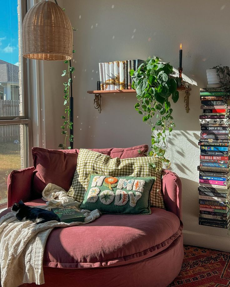 a living room filled with furniture next to a window covered in lots of books and plants