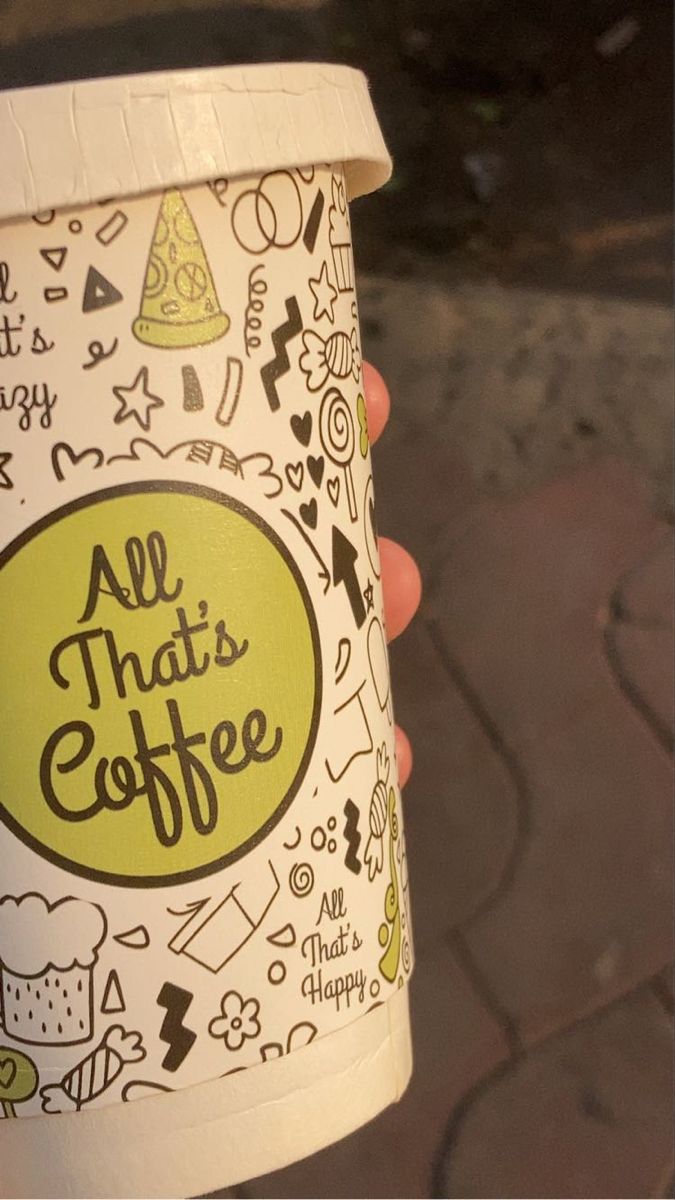 a hand holding up a paper cup that says all that coffee