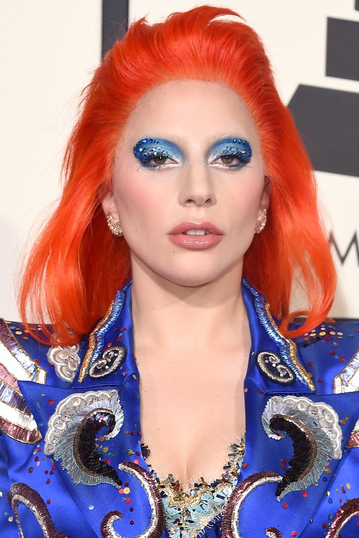 lady with bright red hair and blue eyeshadow at an awards event, dressed in costume