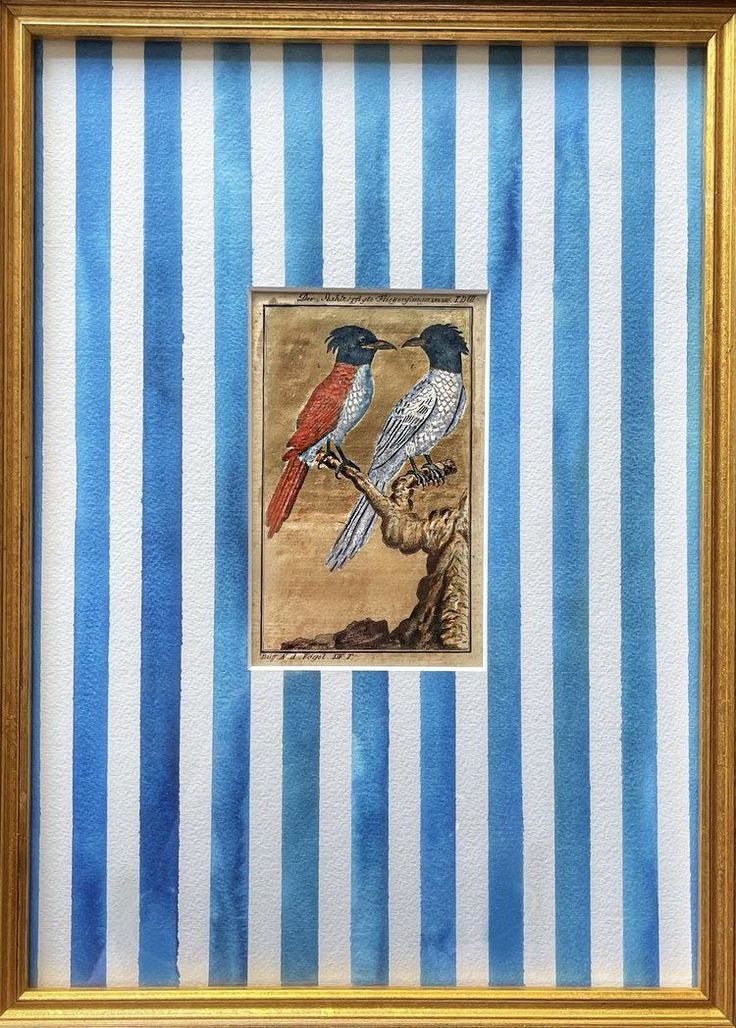 two birds sitting on top of a blue and white striped wall next to a gold frame