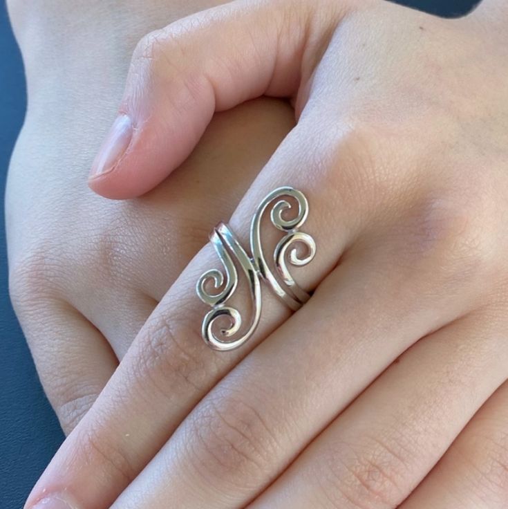 a woman's hand with a silver ring on top of her finger and the letter n in the middle