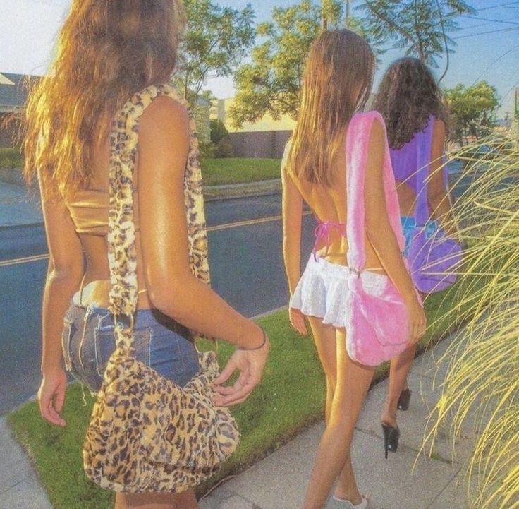 three young women walking down the sidewalk in short skirts and high heeled shoes,