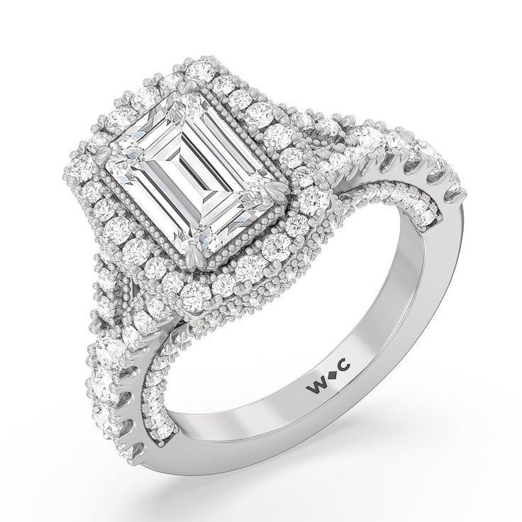 a white gold ring with an emerald cut diamond surrounded by smaller diamonds