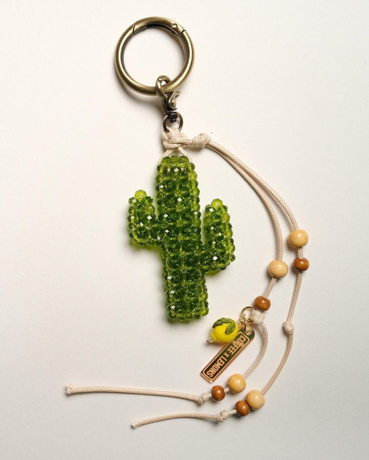 a green cactus keychain with beaded beads on it and a yellow bird