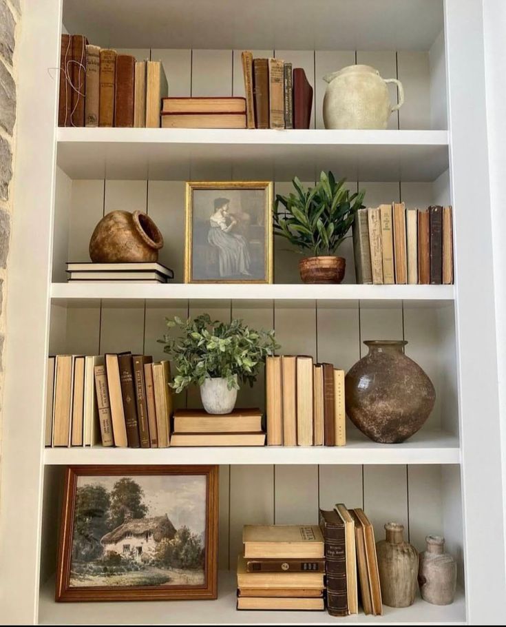 a bookshelf filled with lots of books and vases on top of it