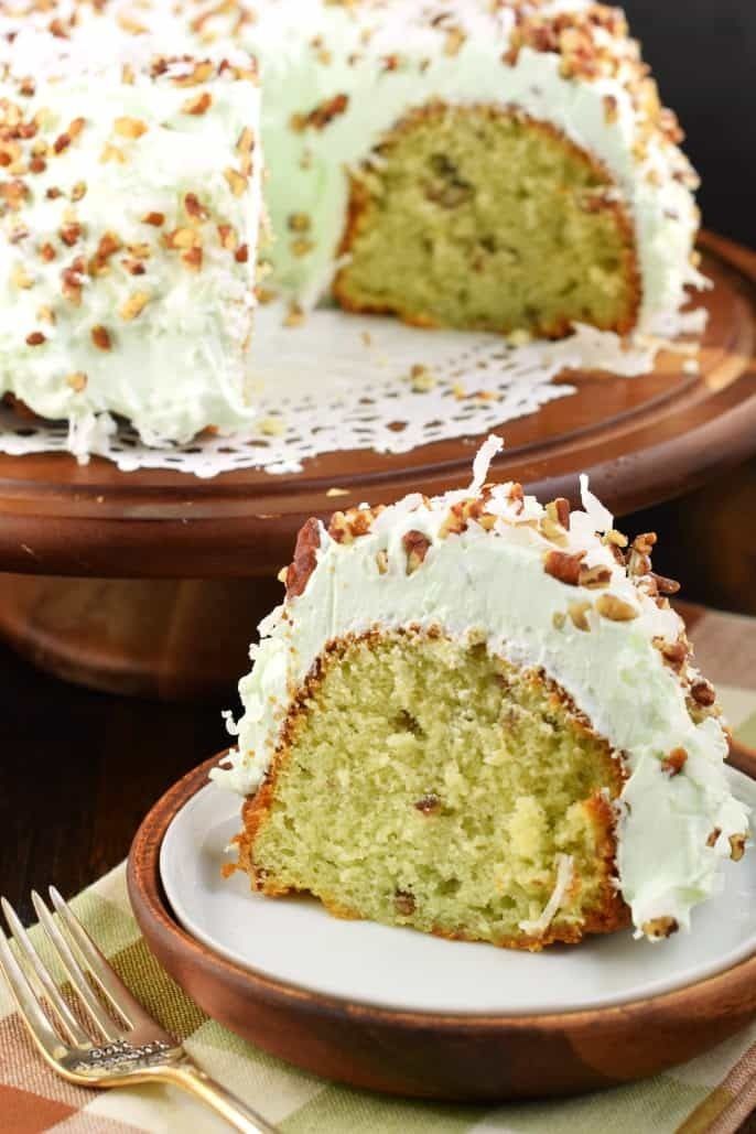 a cake with white frosting and nuts on top is sitting on a plate next to a fork