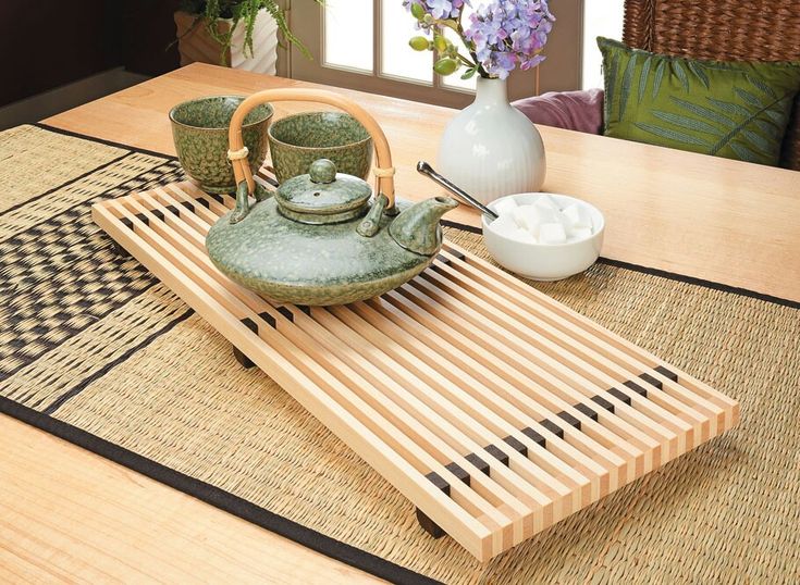 a tea set sitting on top of a wooden table next to a vase and bowl