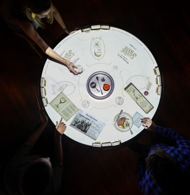 two people sitting at a round table with menus and papers on it, top view from above