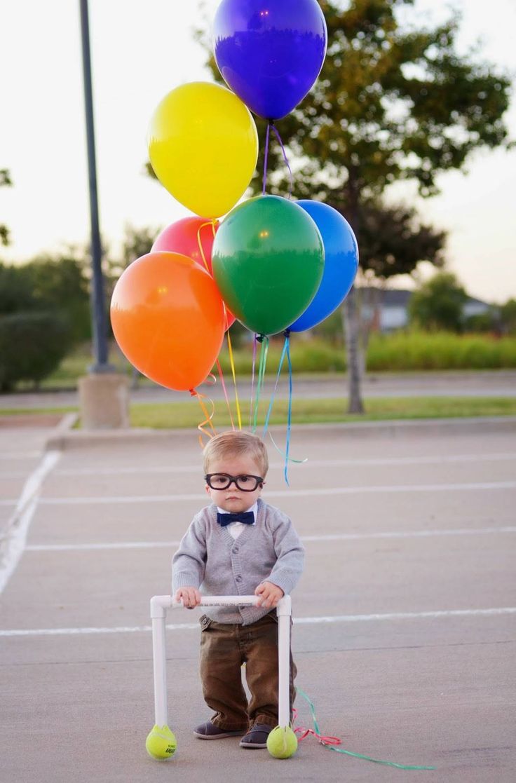 a little boy wearing glasses and holding some balloons