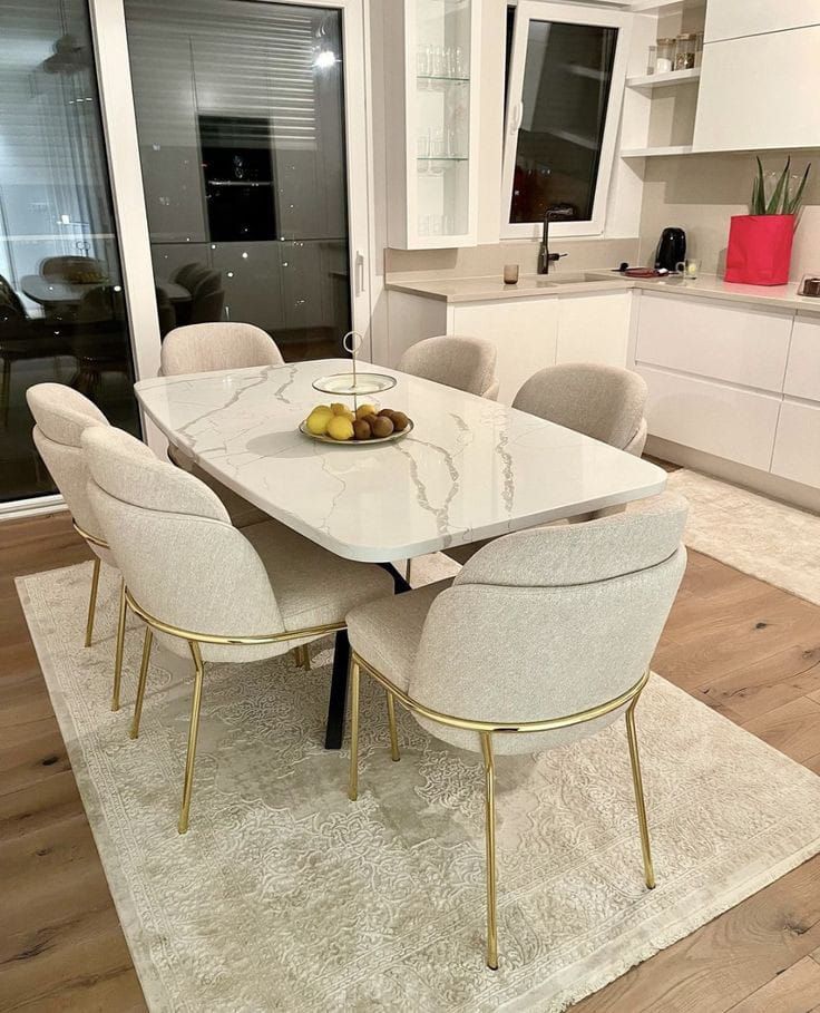 a dining room table with white chairs and fruit on the plate in front of it