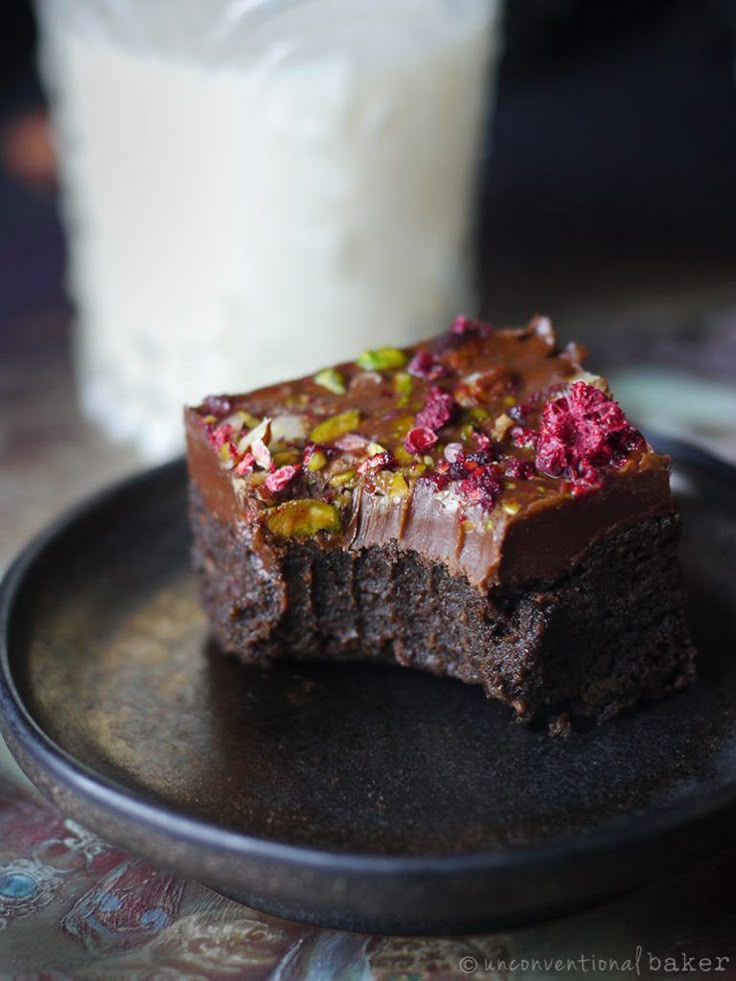 there is a piece of brownie on the plate next to a glass of milk