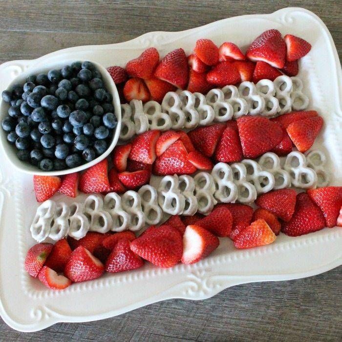 an american flag made out of strawberries and blueberries on a platter with a spoon