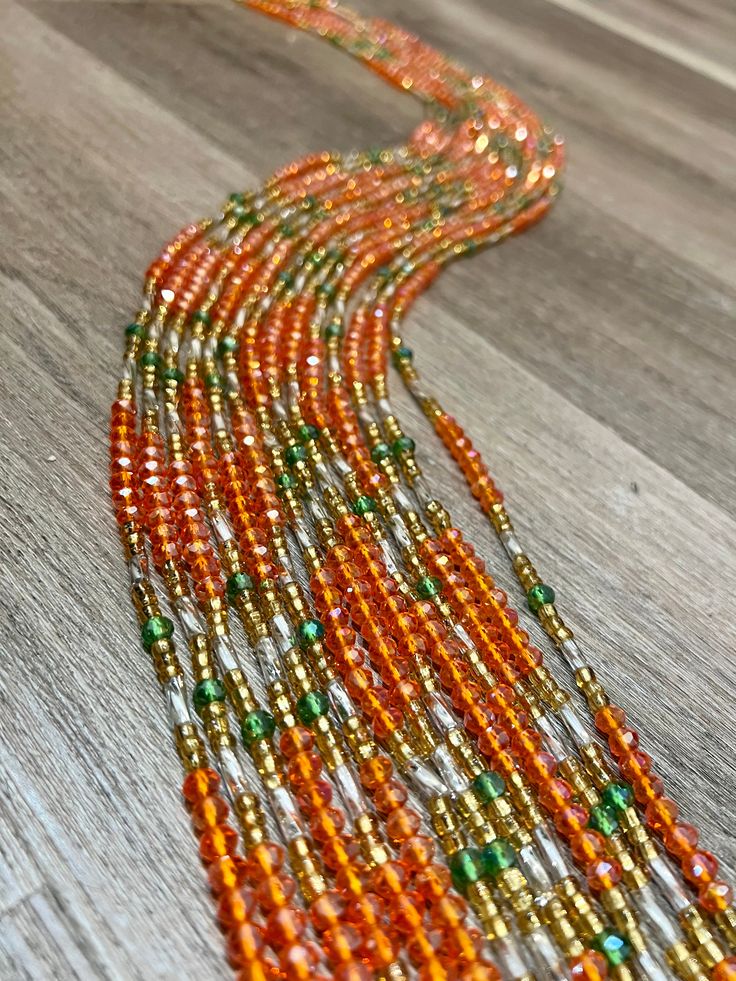 Upgrade your style with Success waist beads. These Ghana-made beads feature bold orange crystals with white and green accents. Elevate your look while enjoying the benefits of traditional waist jewelry. Made with expert craftsmanship, these beads are sure to bring you success in fashion and culture. Orange Faceted Beads In Bohemian Style, Traditional Orange Faceted Beads, Bohemian Orange Faceted Beads, Orange Bohemian Faceted Beads, Traditional Orange Beaded Necklace With Tiny Beads, Traditional Small Orange Beads, Traditional Tiny Orange Beads, Waist Jewelry, Orange Crystals