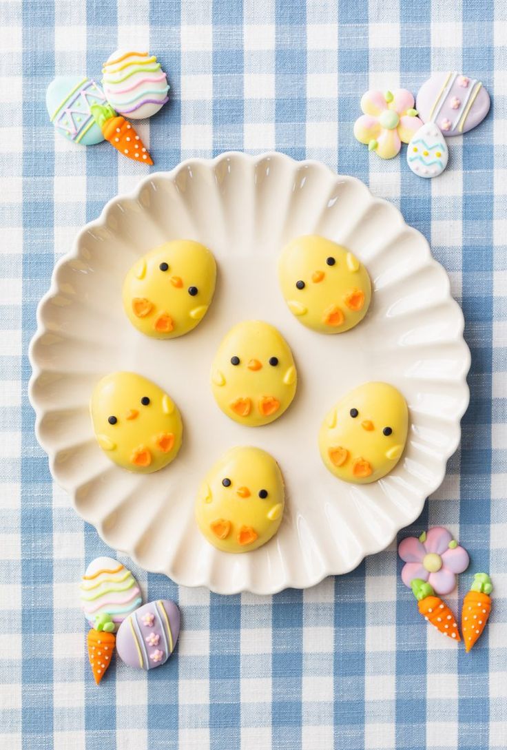 some little yellow chicks are on a white plate with candy candies around them and easter decorations