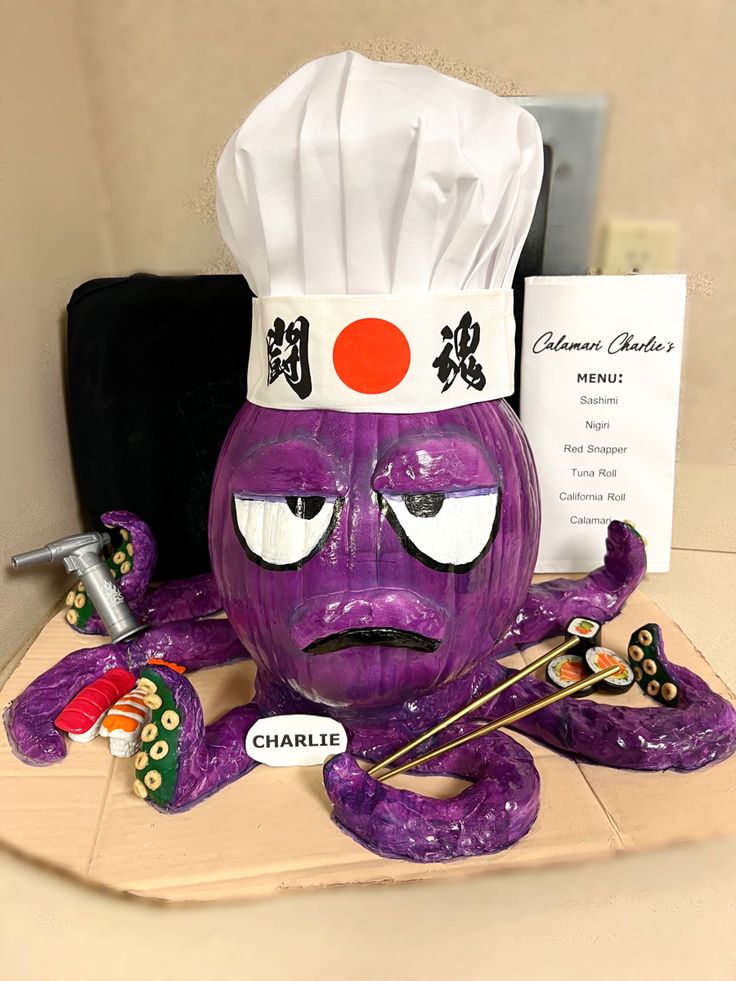 a purple sculpture with a chef's hat on top of it and chopsticks in front of it