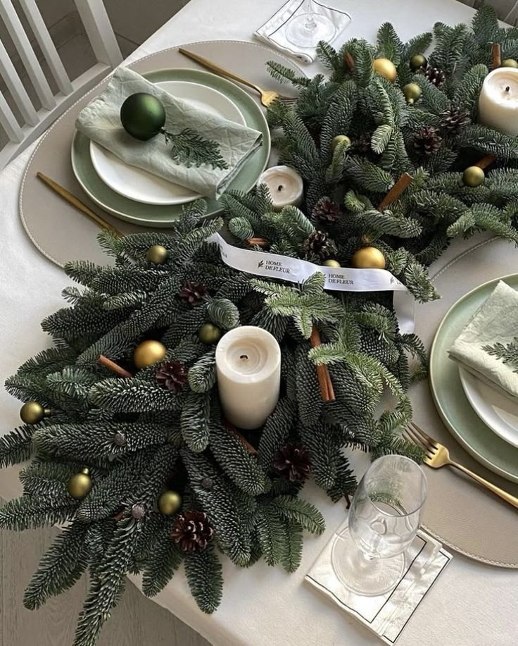 the table is set for christmas dinner with pine cones and evergreen branches, candlesticks and plates