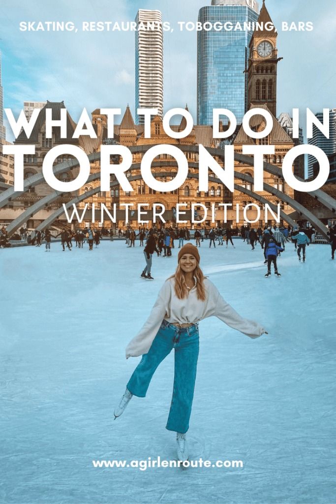 a woman is standing in the snow with her arms spread out and there are buildings behind her