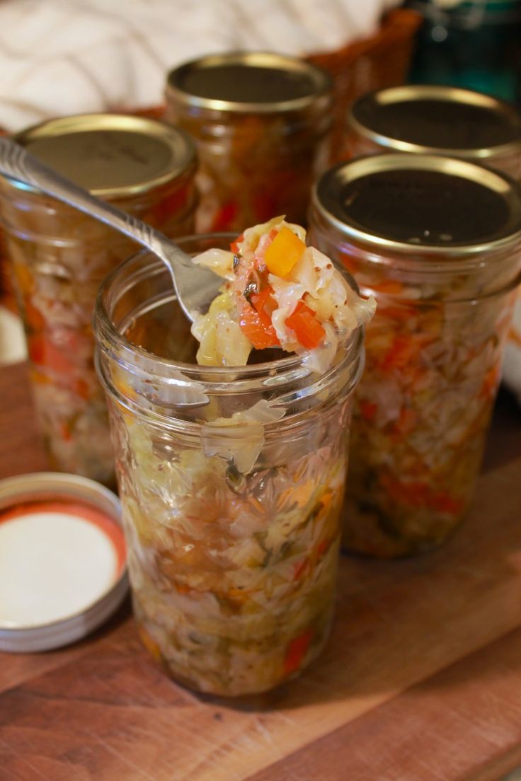 a spoon full of food sitting on top of a wooden cutting board next to jars