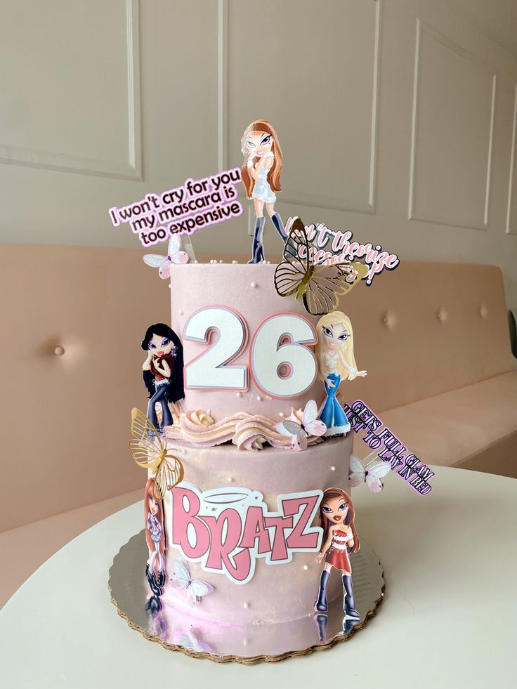 a birthday cake decorated with barbie dolls and stickers on it's top tier