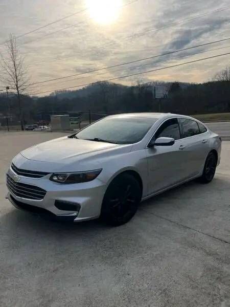 a silver car parked in a parking lot with the sun shining on it's side