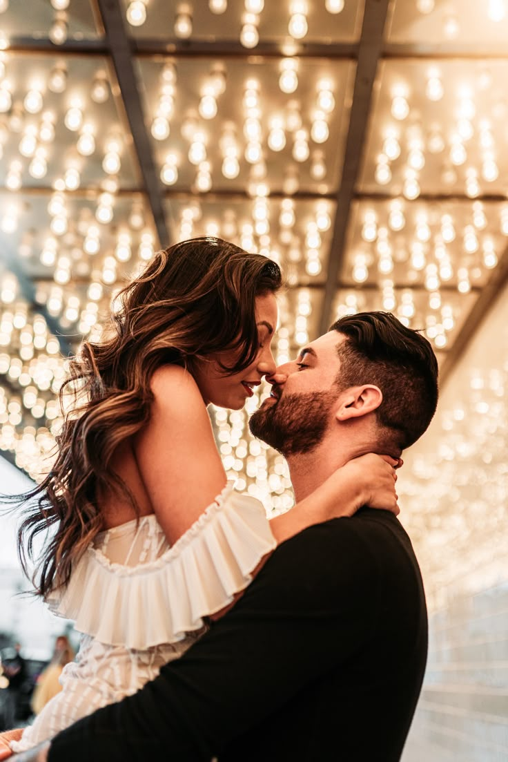 a man and woman kissing in front of lights