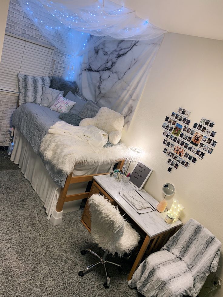 a room with a bed, desk and chair in it that has pictures on the wall