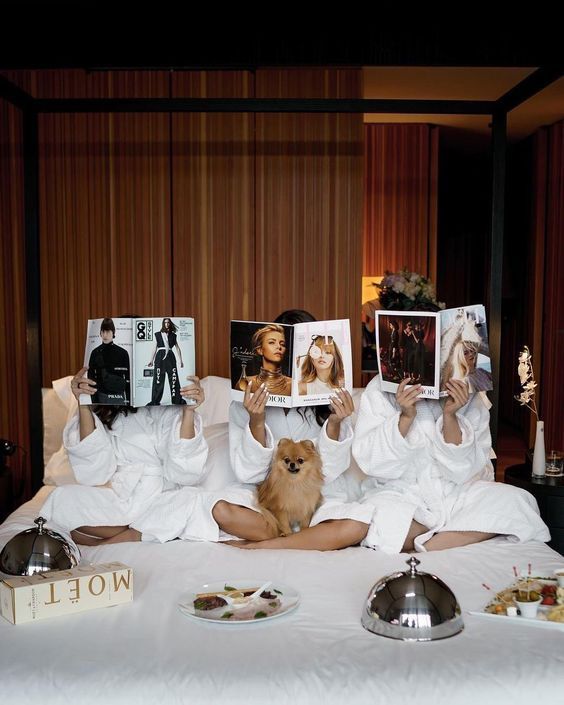 two women and a dog are sitting on a bed with pictures in front of them