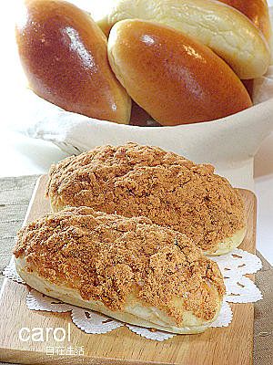 some bread is on a cutting board next to a bowl of buns and a glass of wine