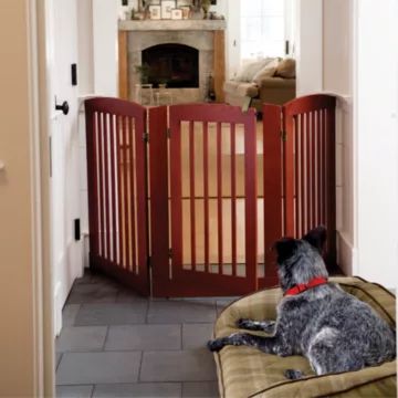 a dog is sitting on a bed in front of a wooden gate that opens to the living room