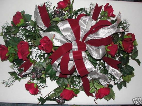 a bouquet of red roses and baby's breath wrapped in silver ribbon on a white box