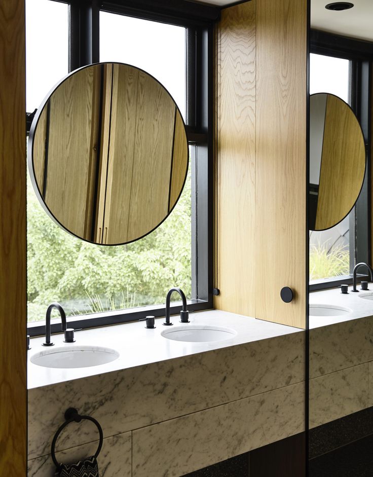 two sinks and mirrors in a bathroom with wood paneling on the windowsills