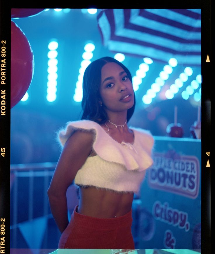 a woman in a crop top and skirt standing next to a blue neon light background