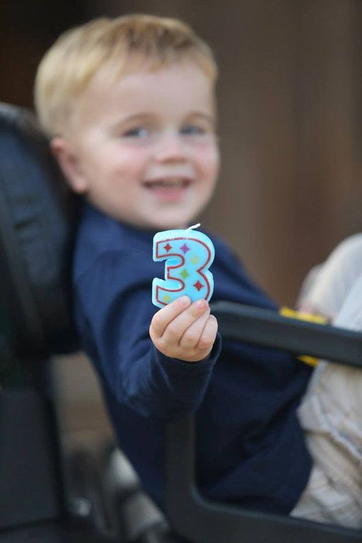 a little boy sitting in a chair holding up a paper number