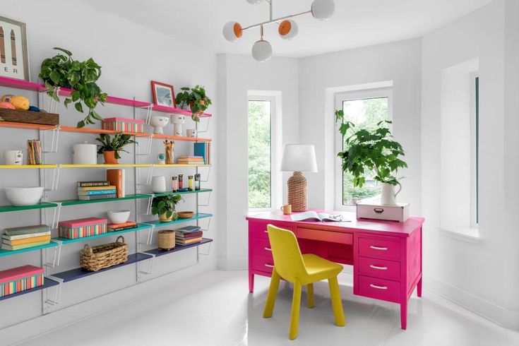 a desk with two yellow chairs in front of it and shelves on the wall behind it