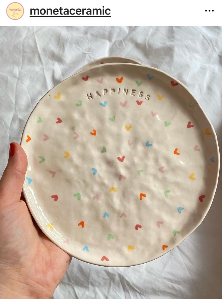 a person holding a plate with the words happiness on it and hearts painted on it