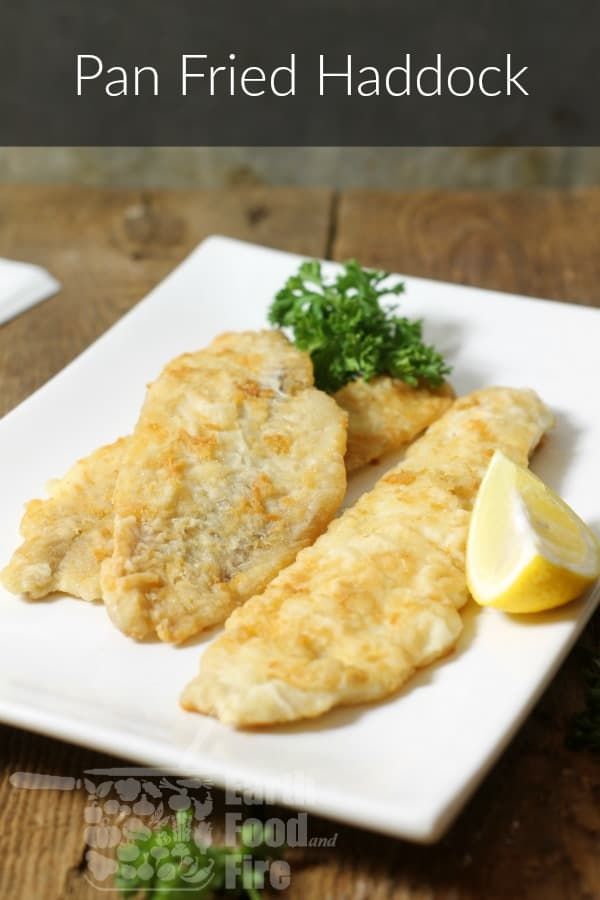 a white plate topped with fried fish next to a lemon wedge and garnished with parsley