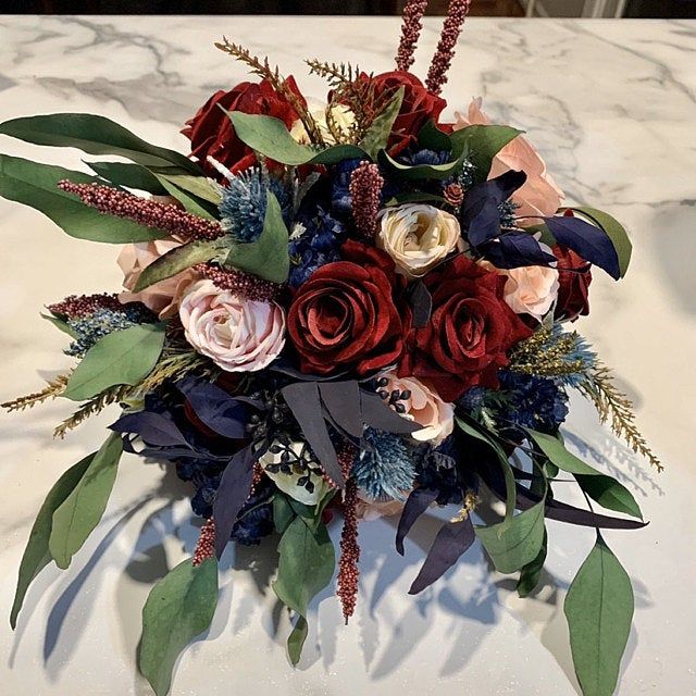 a bridal bouquet with red, white and blue flowers sits on a marble table