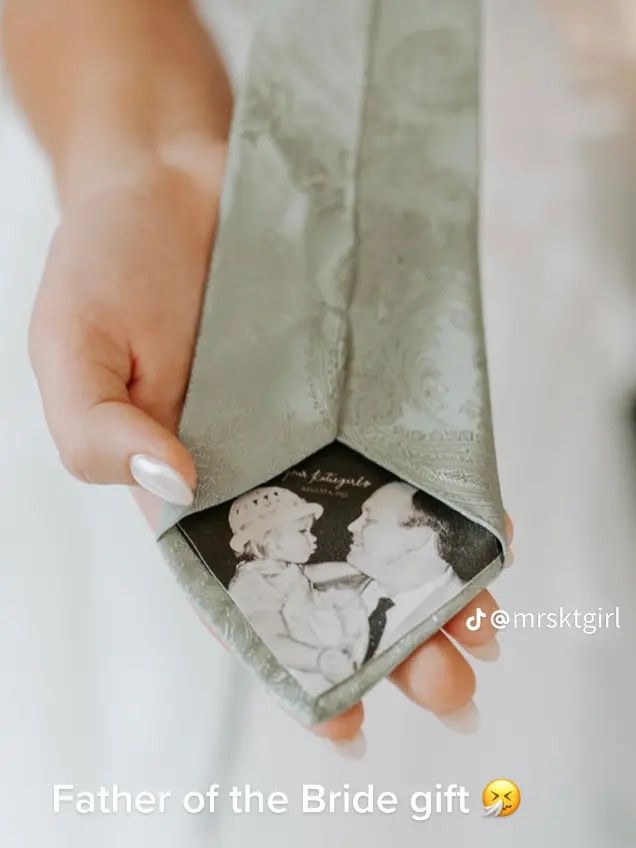 a woman is holding an old photo in her wedding day gift bag with the bride and groom on it