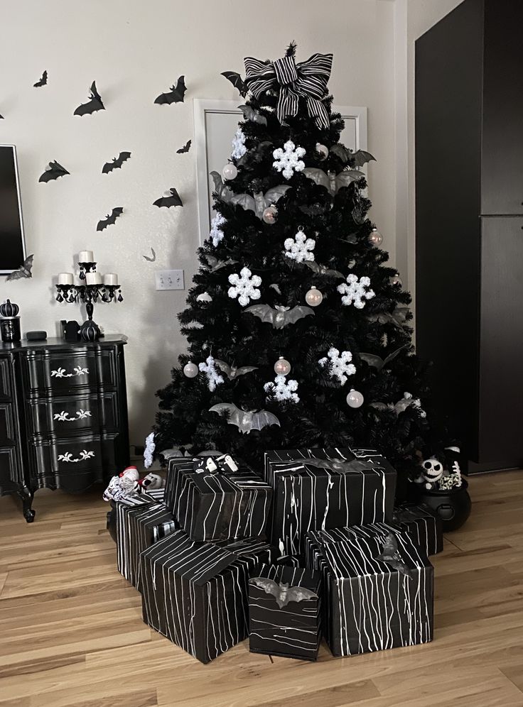 a decorated christmas tree with black and white presents in front of it on the floor