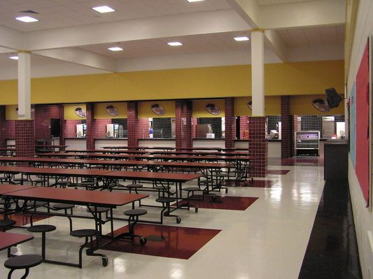 an empty cafeteria with tables and chairs in the middle of the room is yellow and red