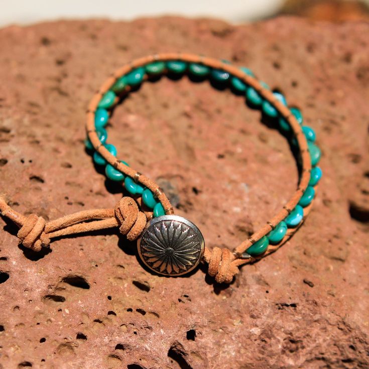 Created by the artists at Alta Studios this Turquoise Bead and Leather Wrap bracelet is hand crafted high in the mountains of Northern New Mexico. Made from genuine high quality turquoise rondelle beads, tan Greek leather cord and cast metal "Concho" button. A beautiful piece of the Southwest! This item is one of a kind - you will receive the exact item pictured. Adjustable length : Approx. 7 3/8" to 8" dia. 12 oz. Shipping Weight Adjustable Turquoise Leather Bracelet In Rustic Style, Artisan Turquoise Beaded Bracelets Adjustable, Adjustable Turquoise Beaded Artisan Bracelets, Southwestern Style Adjustable Gemstone Beads Bracelets, Adjustable Rustic Turquoise Leather Bracelet, Rustic Adjustable Turquoise Beaded Bracelets, Turquoise Waxed Cord Jewelry For Festival, Hand Wrapped Leather Jewelry With Round Beads, Adjustable Beaded Turquoise Leather Bracelet