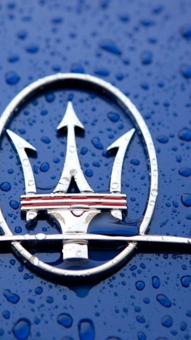 an emblem on the hood of a blue car covered in water droplets and raindrops