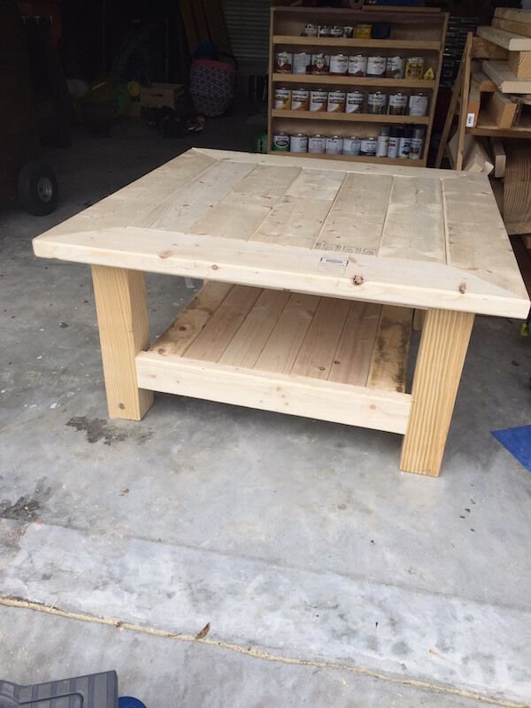 a table made out of pallet wood in a garage with shelves and tools on the floor