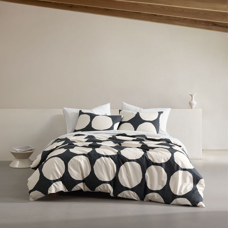 a black and white polka dot comforter set on top of a bed with pillows