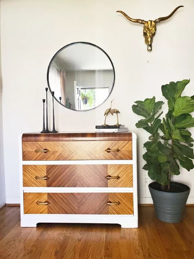 a wooden dresser sitting next to a potted plant on top of a hard wood floor