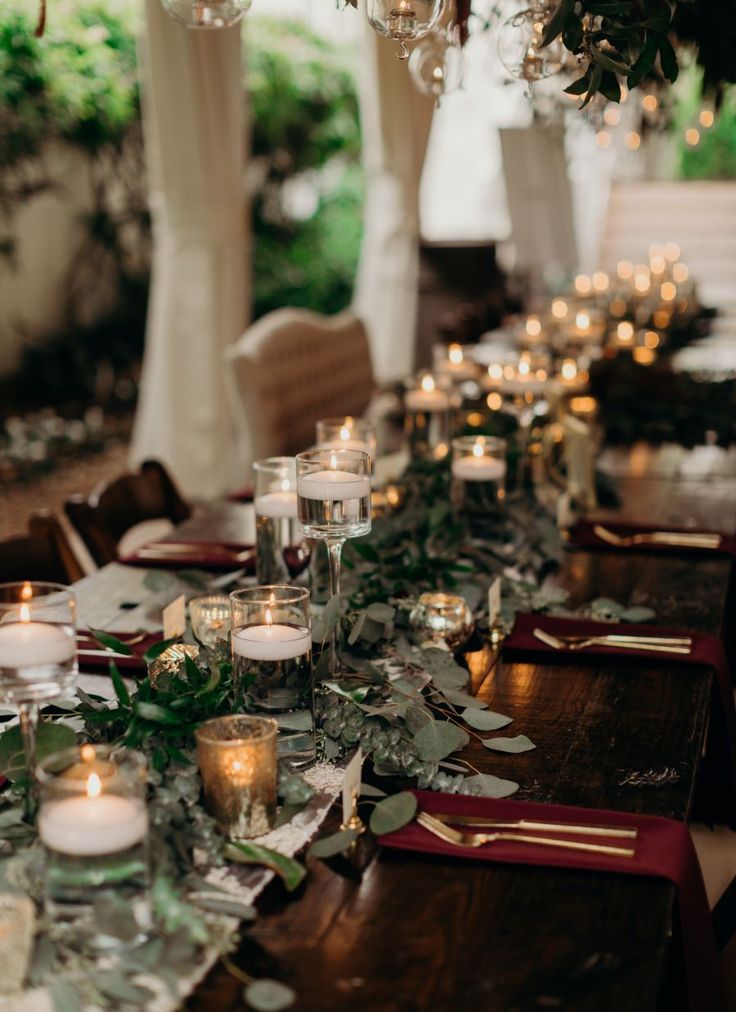 a long table with candles and greenery on it