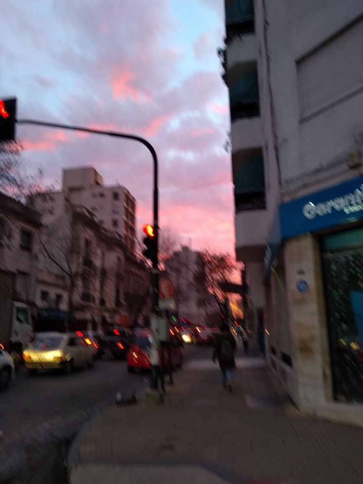 a city street filled with lots of traffic under a pink sky at sunset or dawn