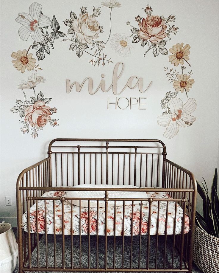 a baby crib in front of a wall with flowers on it and the name miller hope painted on it